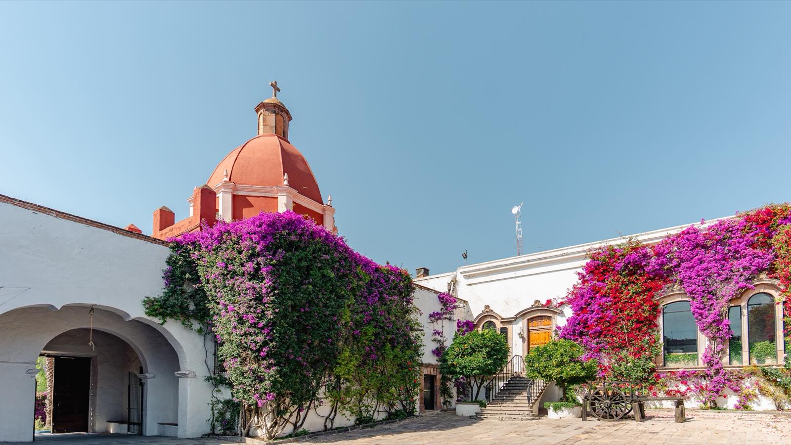 Fachada de cantera de Hacienda Los Cues entre jardines